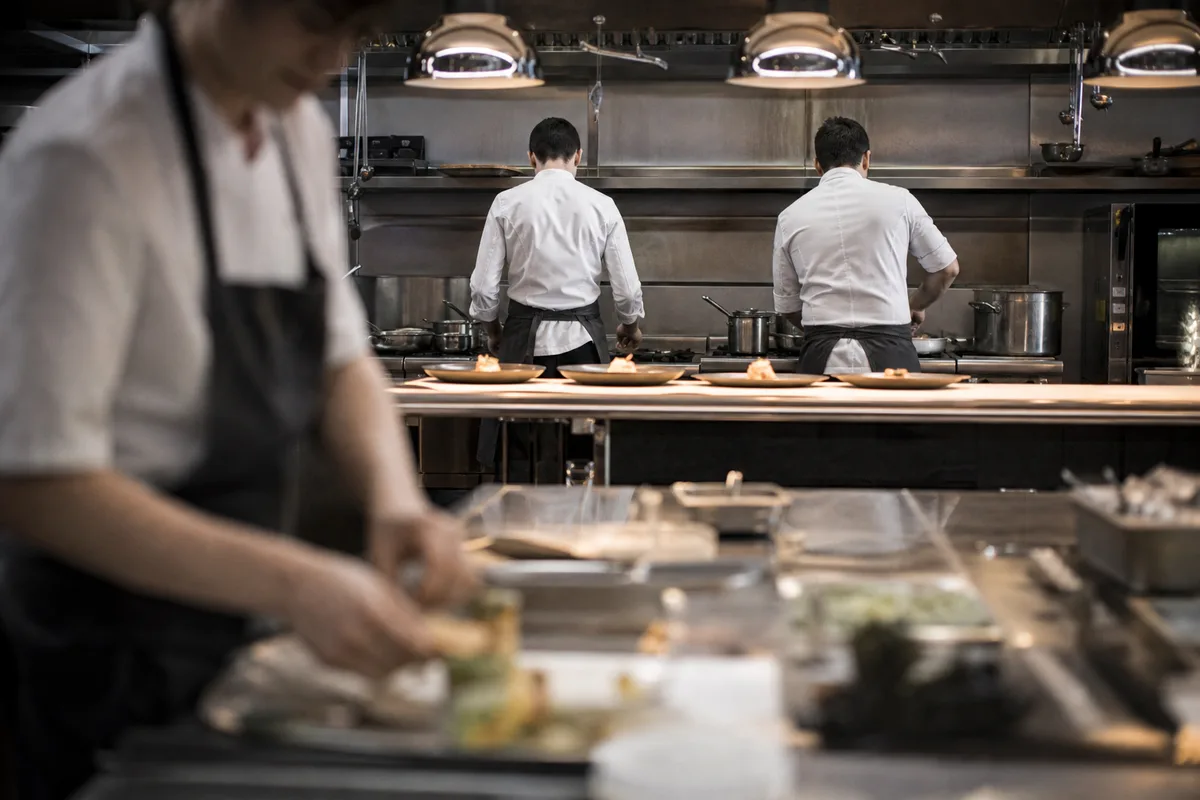 Cuisine de restaurant en plein service, brigade au travail devant les plaques